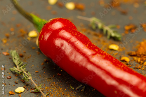 Red hot chili pepper on vintage black table. Colorful dried natural herbs and spices.