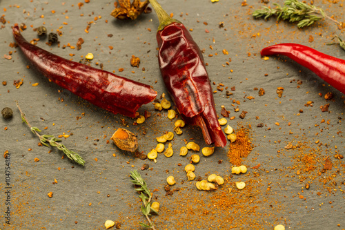 Red hot chili pepper on vintage black table. Colorful dried natural herbs and spices.