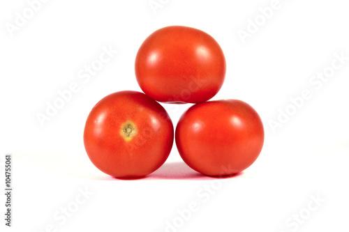 Three red tomatoes on each over pyramid shape macro or close up isolated on white background