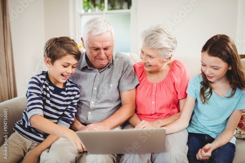 Senior couple using laptop with their grand children