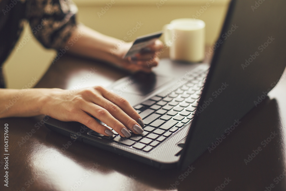 Female holding credit card and typing on laptop Female holding credit card and typing on laptop