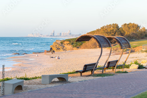 Beach bench cityscape buildings sea shore view, sunset.