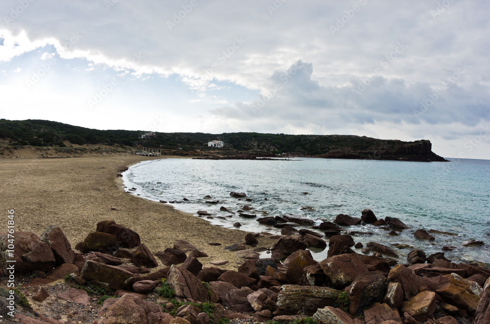 Sandy beach with cliffs at the end in San Pietro island, Sardinia, Italy
