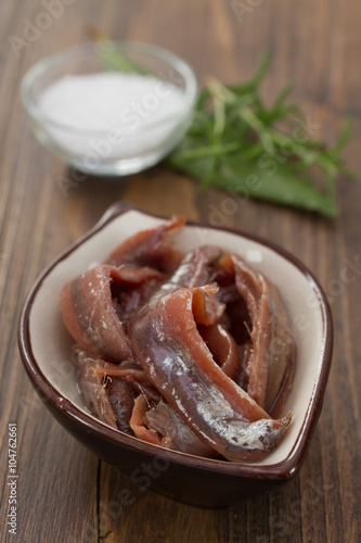 anchovies in dish on brown wooden background
