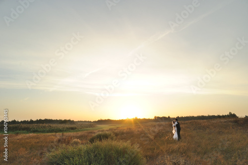 Bride and Groom in the Field at Sunset © UA_Color