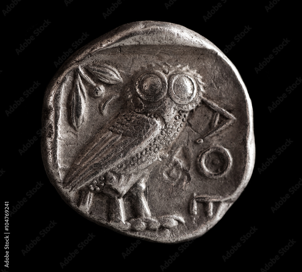 Ancient Greek silver coin with owl on a black background