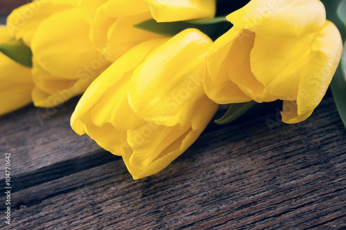 Yellow tulips on rustic wooden background with space for message