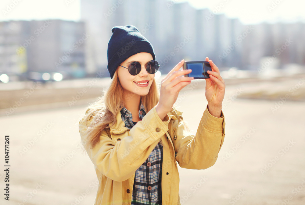 Fashion pretty blonde woman makes selfie-portrait on smartphone