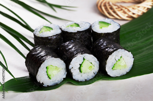 Fotografie sushi roll cucumber chives mini kappa maki in the still life on a tropical leave