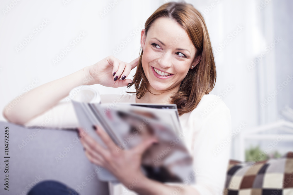 © Sebastian Gauert - Pretty young brown haired girl sitting smiling on couch enjoying reading a fashion magazine © Sebastian Gauert - Pretty young brown haired girl sitting smiling on couch enjoying reading a fashion magazine