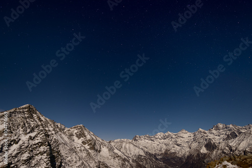 The starry sky above the Alps in winter under moonlight