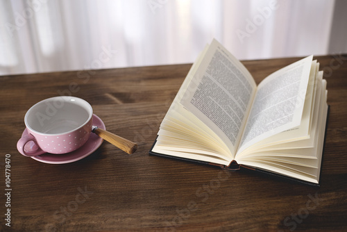Cup of coffee with a book on wooden table