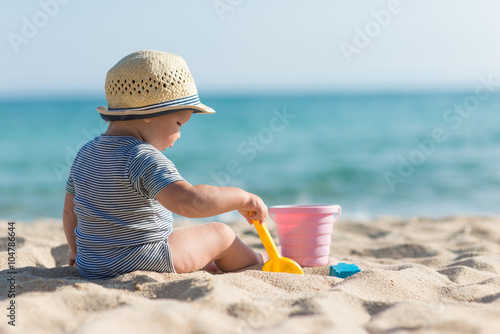 Cute baby on tropical beach playing toys