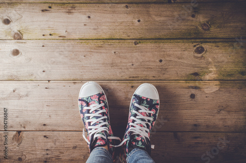 Female sneakers with floral pattern standing on wooden floor
