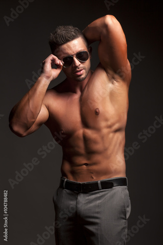 shirtless muscular man in pants and sunglasses posing in studio © vladimirfloyd