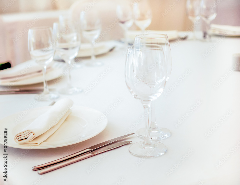 Elegant white wedding table served with cutlery, napkins and wi Elegant white wedding table served with cutlery, napkins and wi