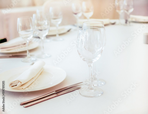 Elegant white wedding table served with cutlery, napkins and wi