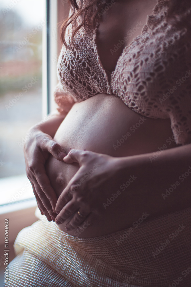 Fototapeta premium Heart from hands, love sign over tummy 
