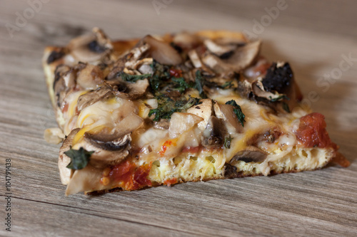 Delicious and mouth watering homemade veggie pizza with mushrooms, sun-dried tomatoes and fresh basil
