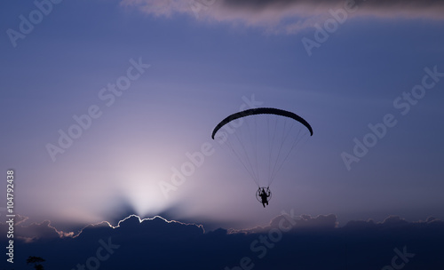 Silhouette paramotor / paraglider flying on sky.