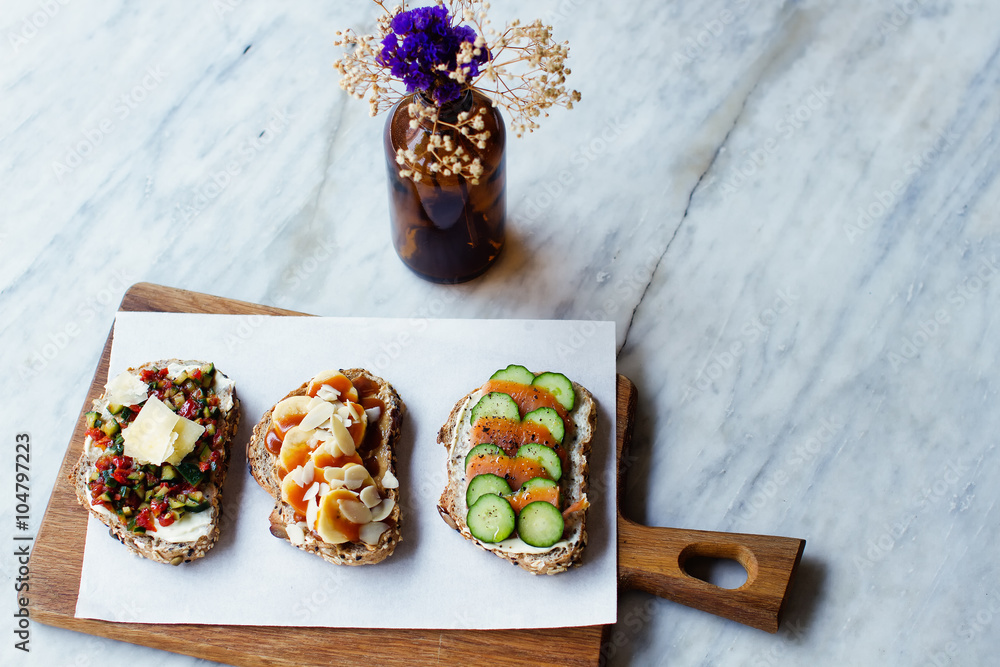 bruschettas with red fish and a cucumber, banana with peanut paste and almonds, tomato with a cucumber, bruschettas on a wooden board, tasty food bruschettas with red fish and a cucumber, banana with peanut paste and almonds, tomato with a cucumber, bruschettas on a wooden board, tasty food