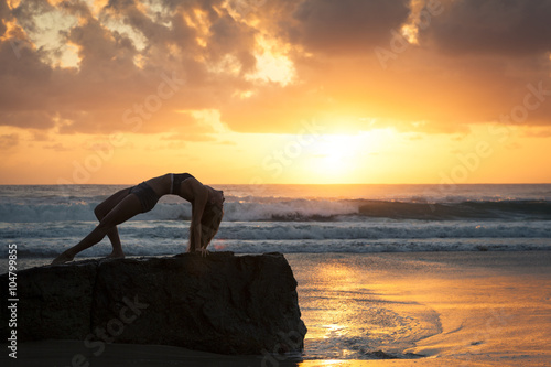 Fit woman stretching on beach at sunrise