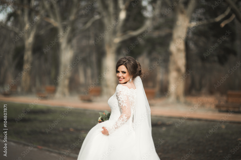 Beautiful bride in the park on her wedding day with bouquet