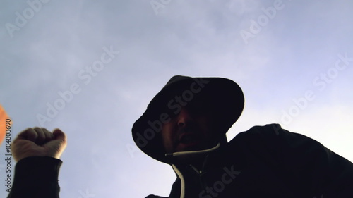 Being punched and mugged by aggressive violent man in hooded jacket on street, victim's pov perspective footage. photo