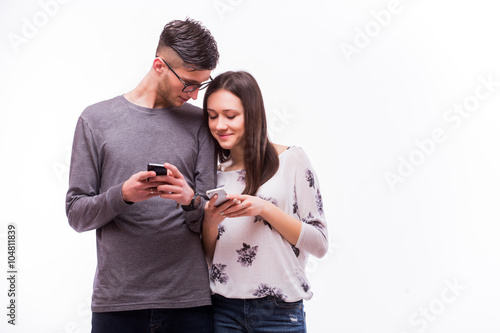 Young hipster couple in love ignoring each other with telephone. Caucasian couple against white background.