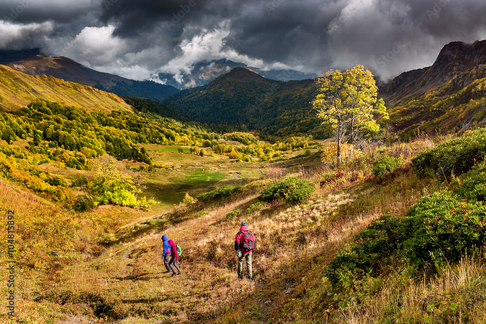 A group of tourists coming down the hill in the Caucasus mountains in autumn