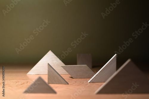 Composition of various geometrical objects - square, triangle, quadrangle - on wooden desk. Shallow depth of field.