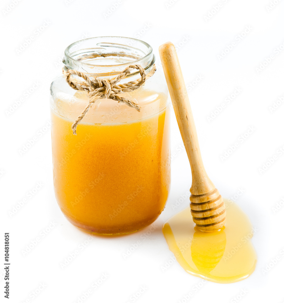 Glass can full of honey and wooden stick on a white background. Glass can full of honey and wooden stick on a white background.