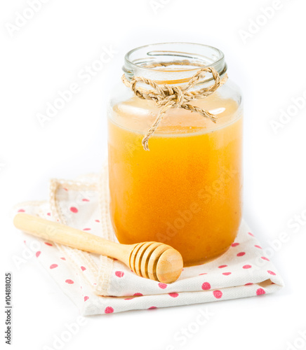 Glass can full of honey and wooden stick on a white background.