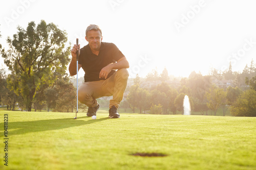 Foto Male Golfer Lining Up Putt On Green