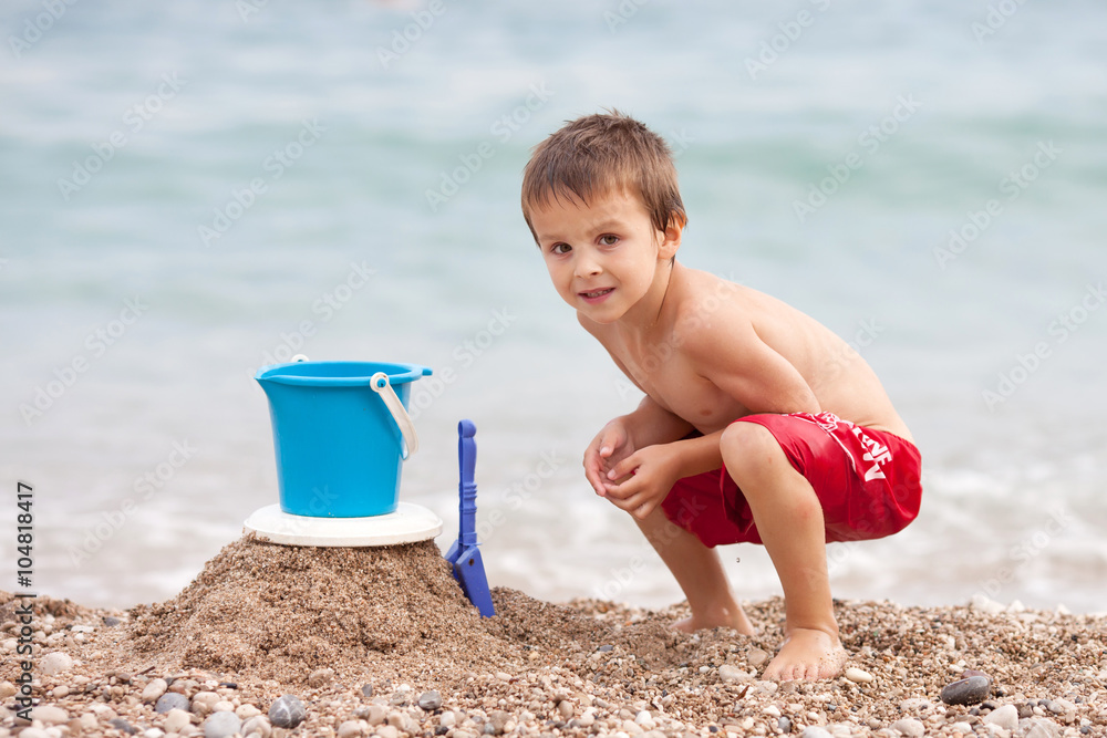 Cute little preschooler boy, playing in the sand on the beach wi Cute little preschooler boy, playing in the sand on the beach wi