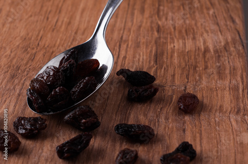 risins on metal spoon on brown wooden table photo