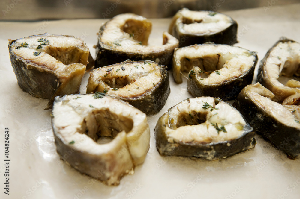 On a black skillet cooked pieces of fish, sturgeon. On a black skillet cooked pieces of fish, sturgeon.