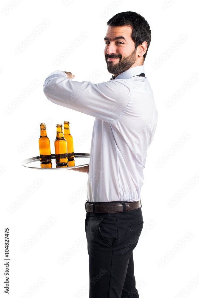 Waiter with beer bottles on the tray pointing back Waiter with beer bottles on the tray pointing back