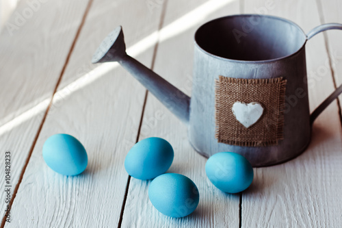 Easter background with blue Easter eggs and watering can on white wooden background