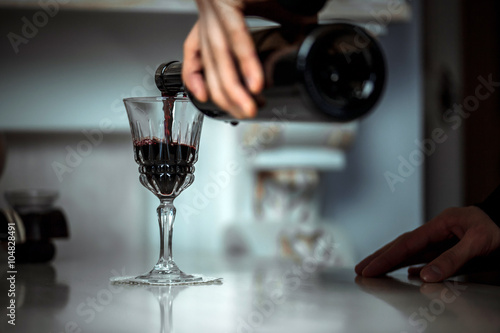 man pours bottle with red wine in a beautiful glass