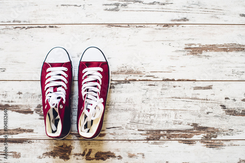 Pair of red trainers on wooden floor top view