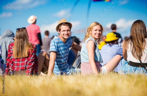 Teenagers at summer music festival, sitting on the grass photo