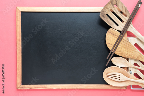 Retro kitchen utensils with empty blackboard on pink background.