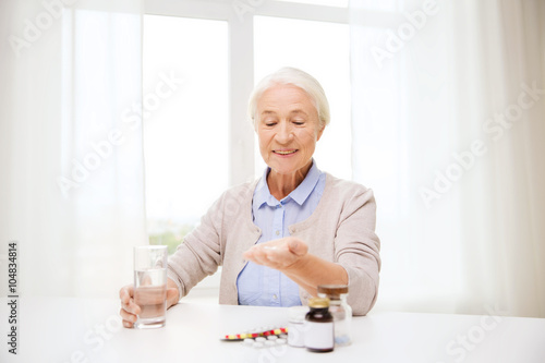 happy senior woman with water and medicine at home