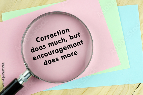 Fotografia Magnifying glass on papers with word quote of Correction does much,but encouragement does more written on it