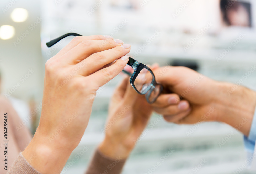 Fototapeta premium close up of hands with glasses at optics store