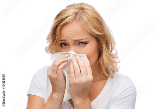 unhappy woman with paper napkin blowing nose