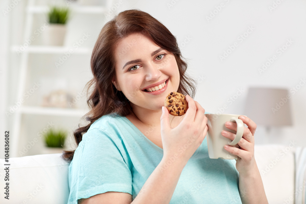 happy plus size woman with cup and cookie at home happy plus size woman with cup and cookie at home