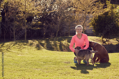Athletic senior woman smiling in a park with her dogs © mavoimages