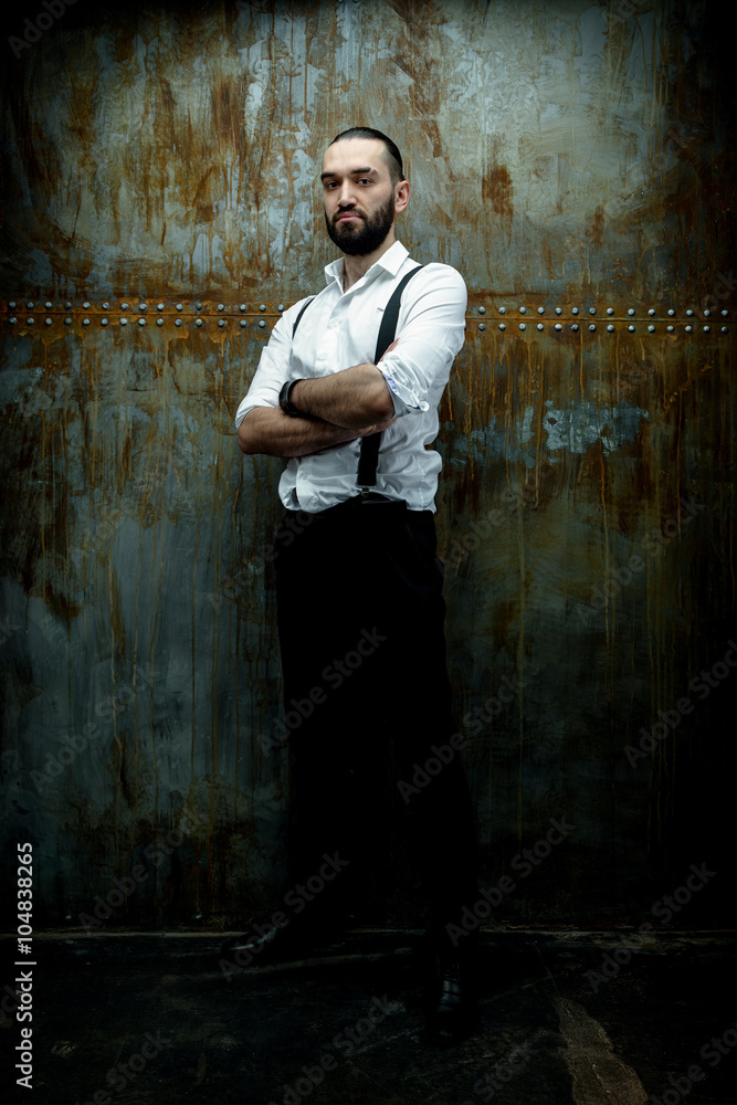 Handsome man posing in white shirt on dark metal wall background